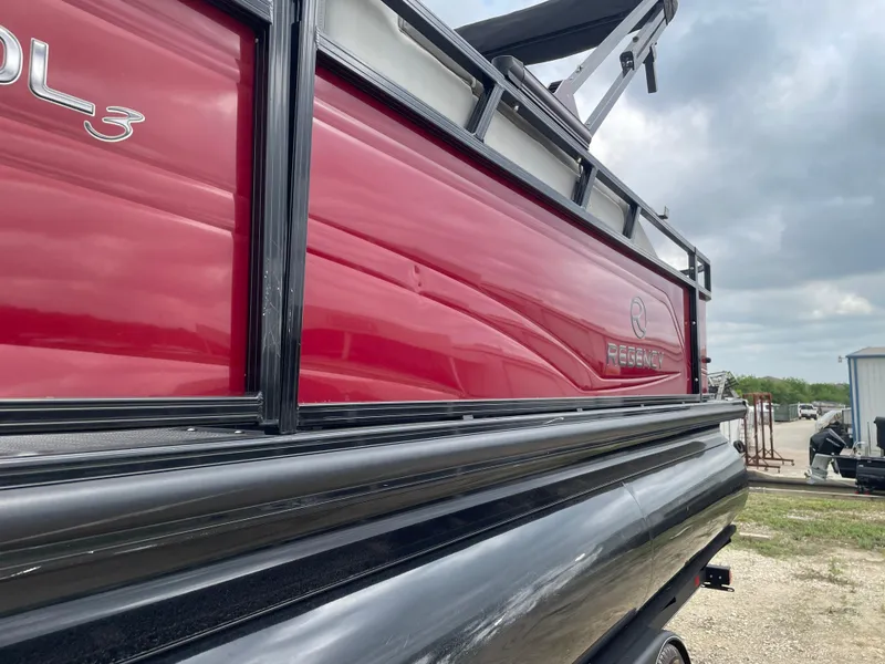Slide: The Image of 2022 Regency 250 DL3 pontoon boat with red and black exterior, docked outdoors. - 11