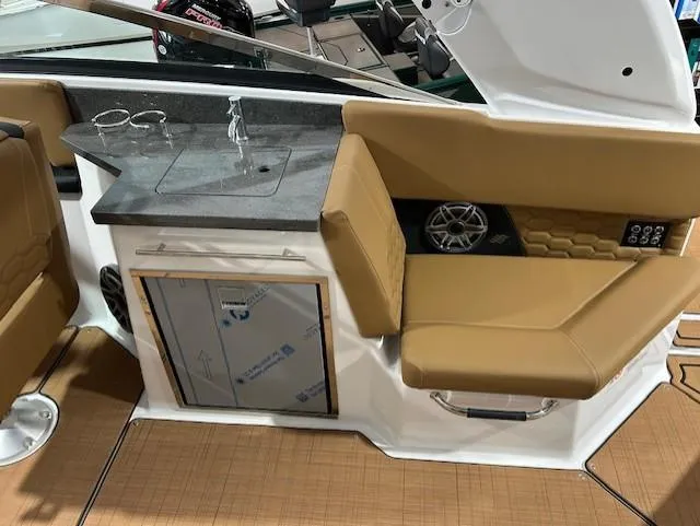 Slide: The Image of 2025 Four Winns H9 OB boat interior with tan seating and compact kitchenette. - 11
