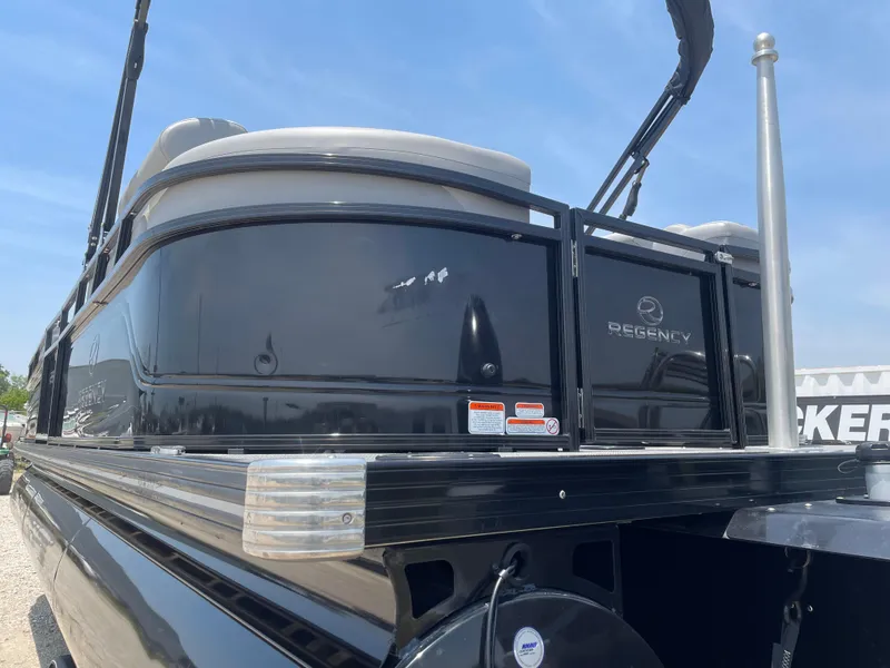 Slide: The Image of 2023 Regency 250 LE3 pontoon boat with sleek black exterior under a clear blue sky. - 10