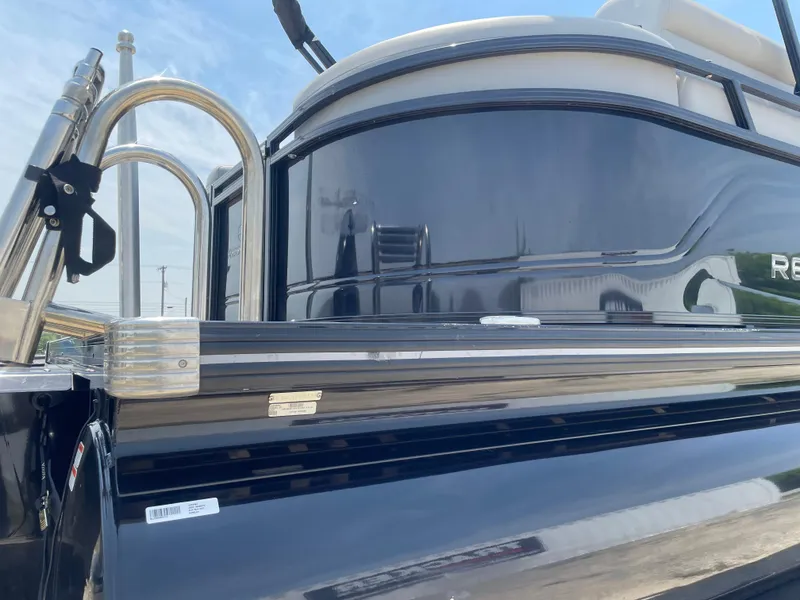 Slide: The Image of 2023 Regency 250 LE3 pontoon boat, sleek black exterior, stainless steel railings. - 11