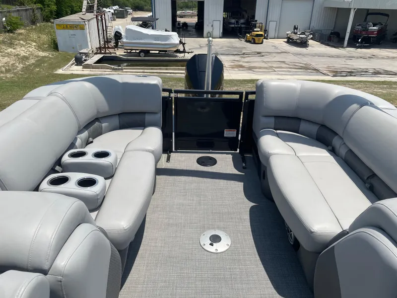 Slide: The Image of 2023 Regency 250 LE3 pontoon boat with spacious seating and cup holders, docked near a storage facility. - 15