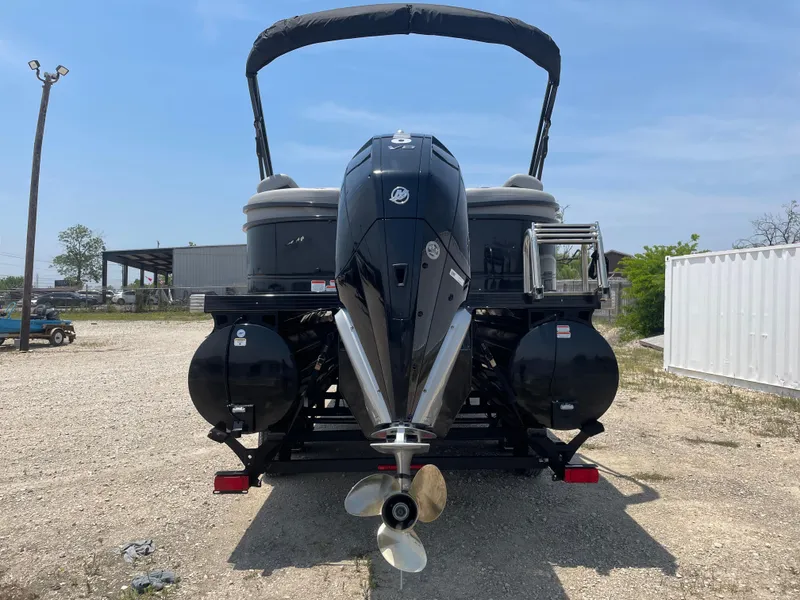 Slide: The Image of 2023 Regency 250 LE3 pontoon boat with powerful outboard motor, parked on gravel. - 3