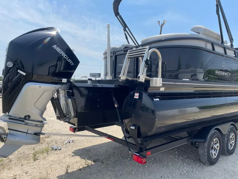 Slide: The Image of 2023 Regency 250 LE3 pontoon boat with Mercury outboard engine, parked on a trailer. - 4