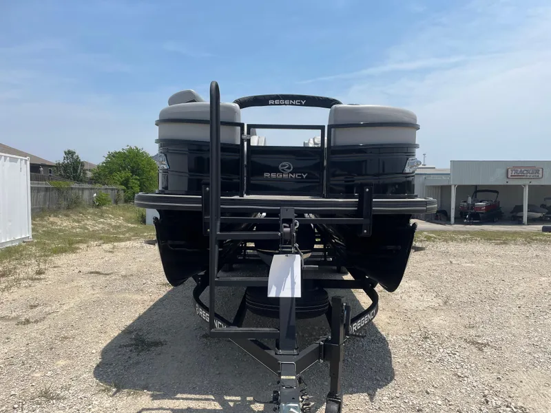 Slide: The Image of 2023 Regency 250 LE3 pontoon boat on trailer, parked outdoors. - 6