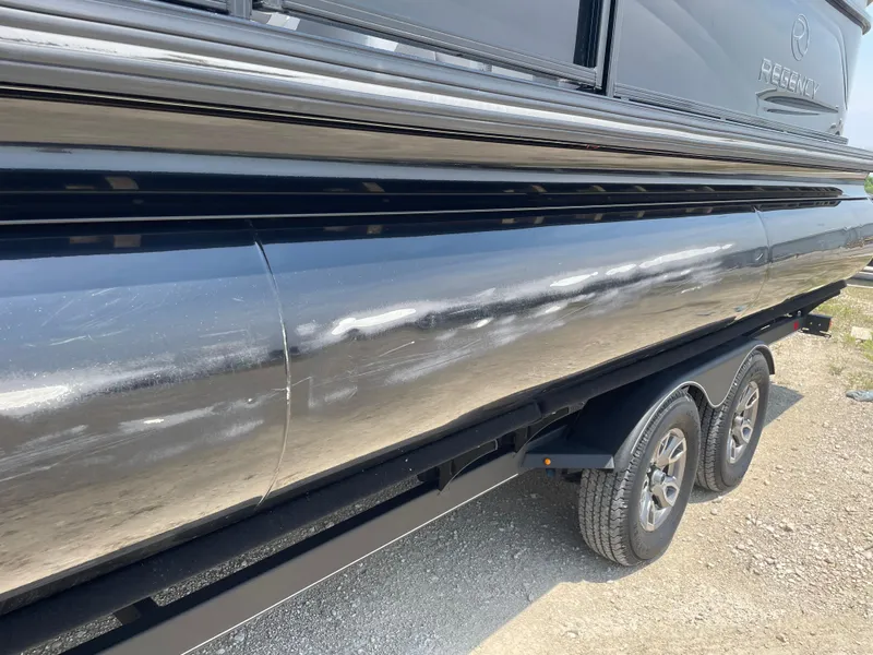 Slide: The Image of 2023 Regency 250 LE3 pontoon boat on trailer, side view, shiny black exterior. - 8