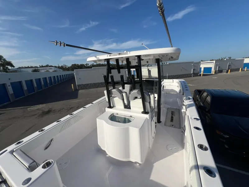 Slide: The Image of 2025 Twin Vee 280 GFX2 CC boat with fishing rod holders, docked in a storage facility. - 13