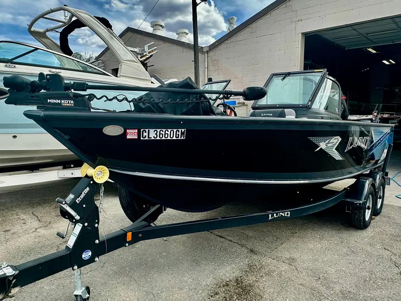 Slide: The Image of 2021 Lund 1875 Crossover XS boat on trailer, parked outside a building. - 1