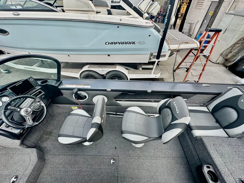 Slide: The Image of 2021 Lund 1875 Crossover XS boat interior with seating and steering wheel, in a showroom. - 12