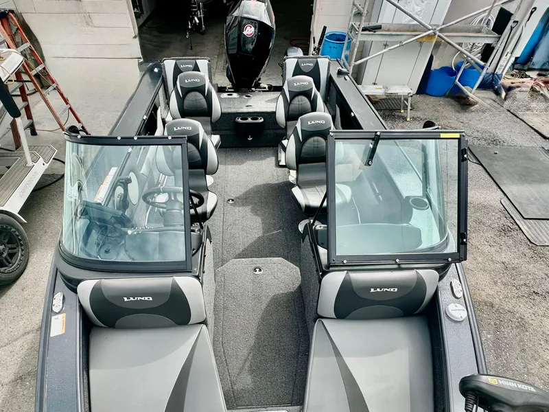 Slide: The Image of 2021 Lund 1875 Crossover XS boat interior with seating and windshield, parked in a garage. - 18