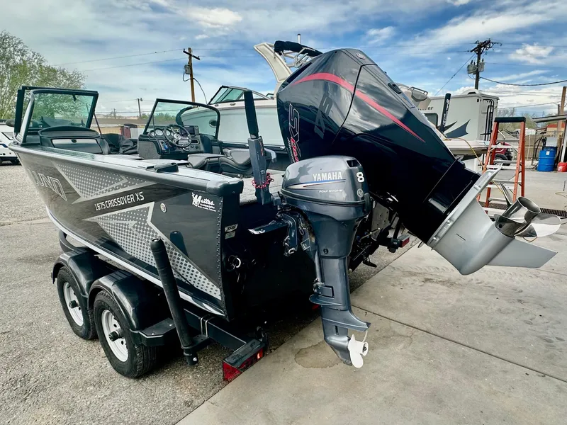 Slide: The Image of 2021 Lund 1875 Crossover XS boat with dual outboard motors on a trailer. - 3
