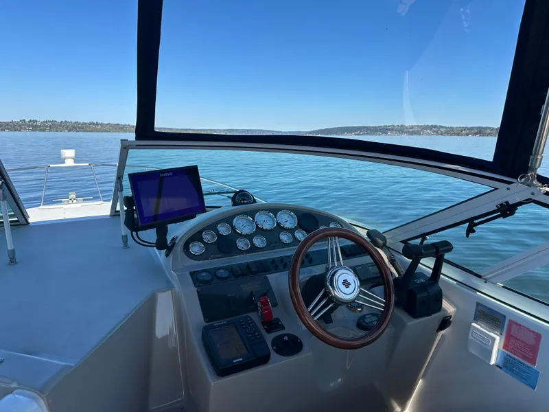 Slide: The Image of 2004 Cruisers Express boat helm with steering wheel and navigation equipment on calm water. - 13