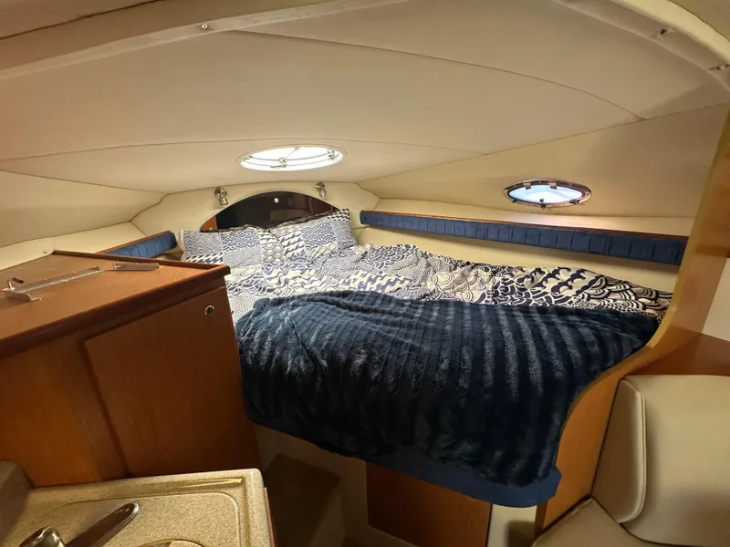 Slide: The Image of 2004 Cruisers Express cabin interior with cozy bed and porthole windows. - 24