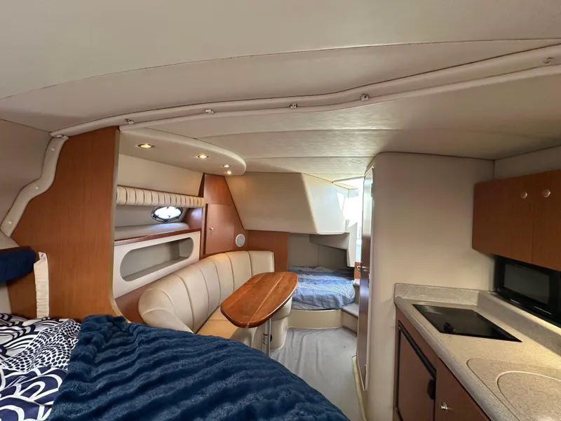 Slide: The Image of Interior of a 2004 Cruisers Express boat with seating, table, and kitchenette. - 25