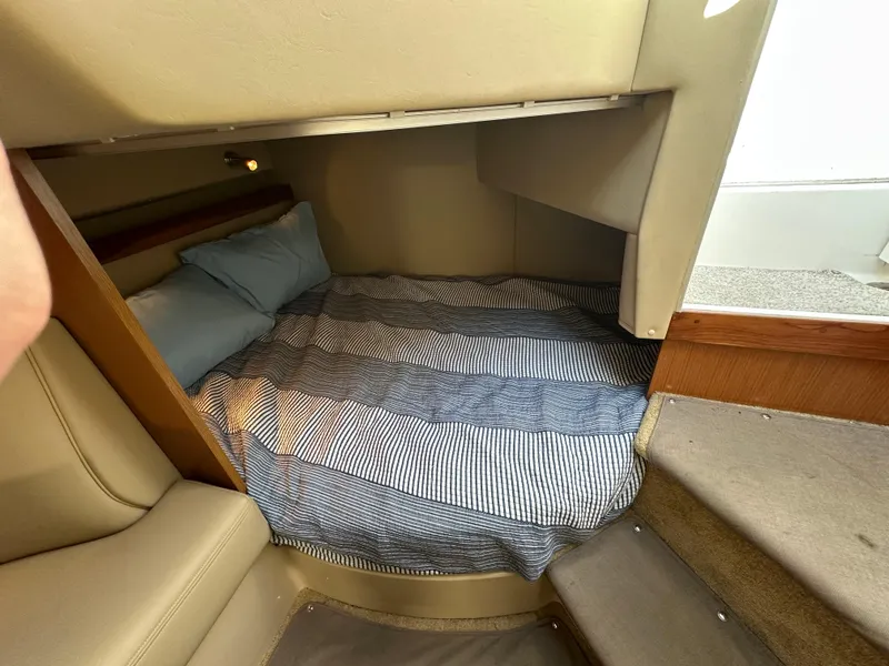 Slide: The Image of 2004 Cruisers Express cabin interior with cozy bed and striped bedding. - 27