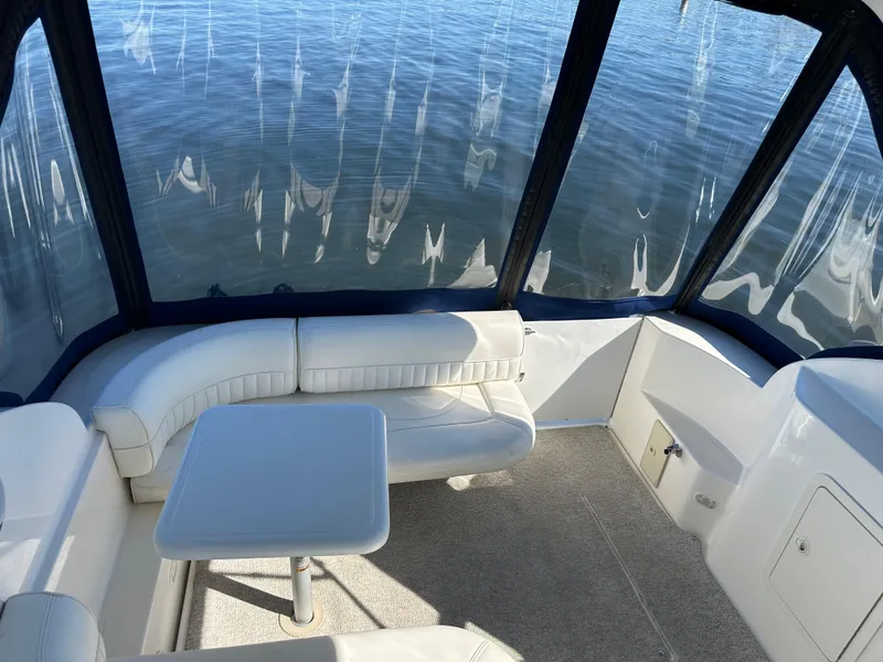 Slide: The Image of 2004 Cruisers Express boat interior with white seating and table, overlooking calm water. - 6