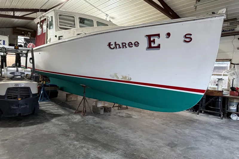 Slide: The Image of 1990 BEALS Lobster Boat "Three E's" in a workshop, supported by a forklift. - 29