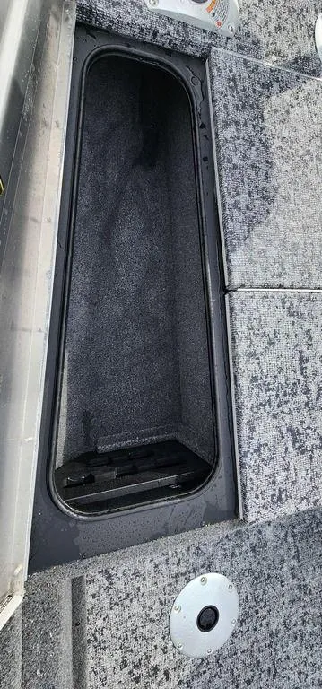 Slide: The Image of 2024 Tracker Pro Team 175 TF boat storage compartment with gray carpet interior. - 22