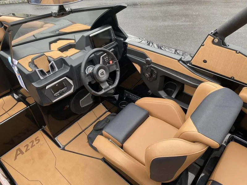 Slide: The Image of 2025 Axis A225 boat interior with tan and black seating, modern dashboard, and steering wheel. - 10