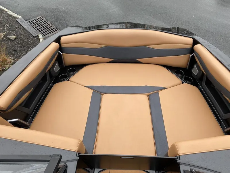 Slide: The Image of 2025 Axis A225 boat interior with tan and black seating, cup holders, and sleek design. - 12