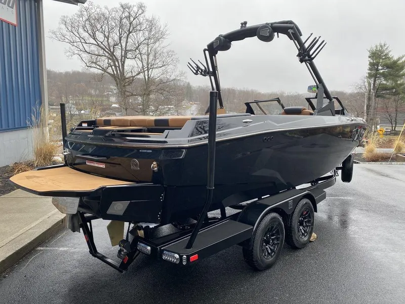 Slide: The Image of 2025 Axis A225 boat on trailer, sleek black design, parked outdoors on a rainy day. - 3