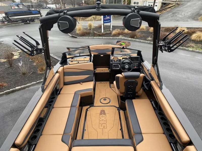 Slide: The Image of 2025 Axis A225 boat interior with tan and black seating, advanced dashboard, and wakeboard racks. - 9