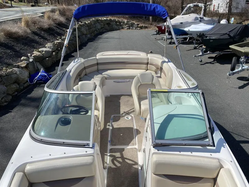 Slide: The Image of 2005 Chaparral 216 Sunesta boat with beige seating and blue canopy, parked outdoors. - 15