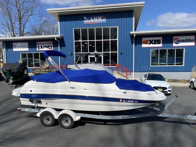 Slide: The Image of 2005 Chaparral 216 Sunesta boat on trailer, parked outside a blue building. - 19