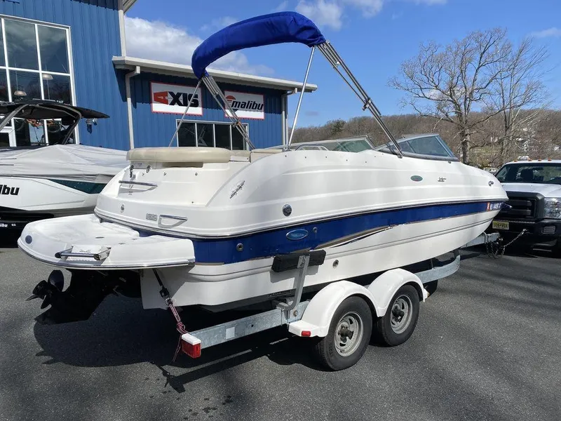 Slide: The Image of 2005 Chaparral 216 Sunesta boat on trailer, parked outdoors near a blue building. - 3
