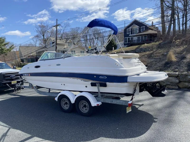 Slide: The Image of 2005 Chaparral 216 Sunesta boat on trailer, parked outdoors under blue sky. - 6