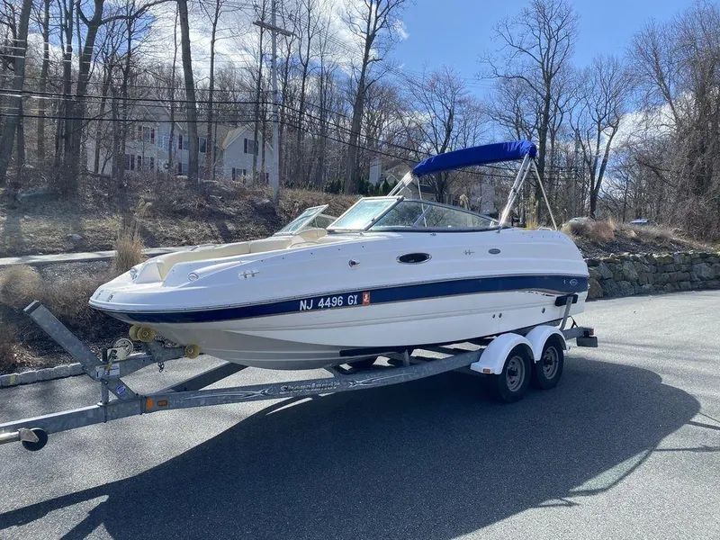 Slide: The Image of 2005 Chaparral 216 Sunesta boat on trailer, parked on a road with trees in background. - 7