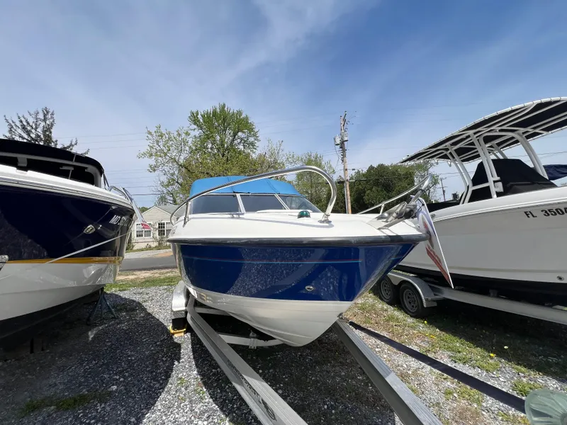 Slide: The Image of 2006 Bayliner 212 boat on trailer, parked outdoors under clear sky. - 0