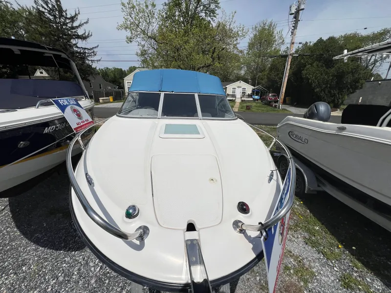 Slide: The Image of 2006 Bayliner 212 boat with blue canopy, displayed outdoors between other boats. - 1