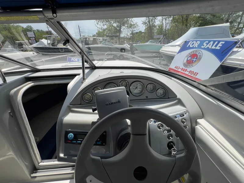 Slide: The Image of 2006 Bayliner 212 boat dashboard with steering wheel and gauges, for sale sign visible. - 2