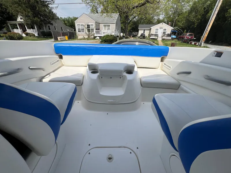 Slide: The Image of 2006 Bayliner 212 boat interior with blue and white seating, parked in a residential area. - 5