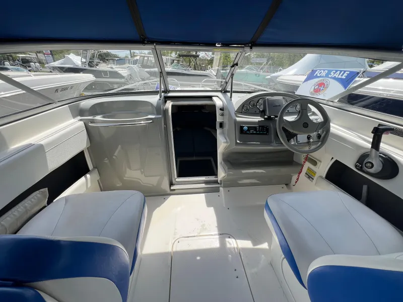 Slide: The Image of 2006 Bayliner 212 boat interior with blue and white seating, steering wheel, and "For Sale" sign. - 6