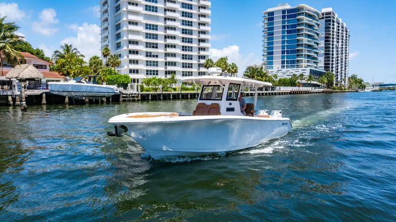 Slide: The Image of 2023 Sea Pro 320 DLX Offshore boat cruising near waterfront buildings. - 10