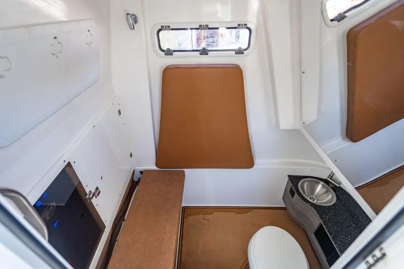 Slide: The Image of 2023 Sea Pro 320 DLX Offshore cabin interior with seating, sink, and toilet. - 26