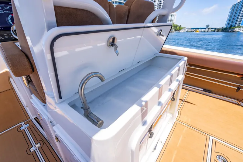 Slide: The Image of 2023 Sea Pro 320 DLX Offshore boat with open storage compartment and faucet, docked by the water. - 37