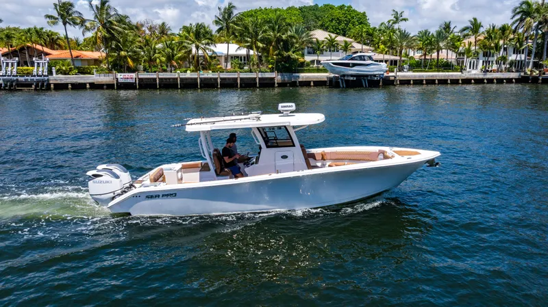 Slide: The Image of 2023 Sea Pro 320 DLX Offshore boat cruising on a sunny day near a tropical shoreline. - 46