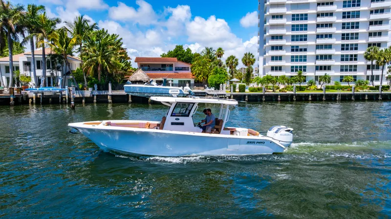 Slide: The Image of 2023 Sea Pro 320 DLX Offshore boat cruising near waterfront buildings and palm trees. - 47
