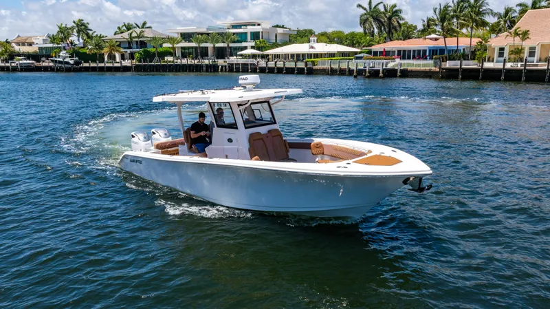 Slide: The Image of 2023 Sea Pro 320 DLX Offshore boat cruising on a sunny day near waterfront homes. - 48