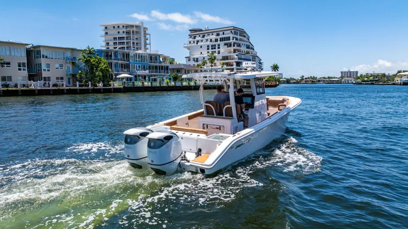Slide: The Image of 2023 Sea Pro 320 DLX Offshore boat cruising on a sunny waterfront with modern buildings. - 49