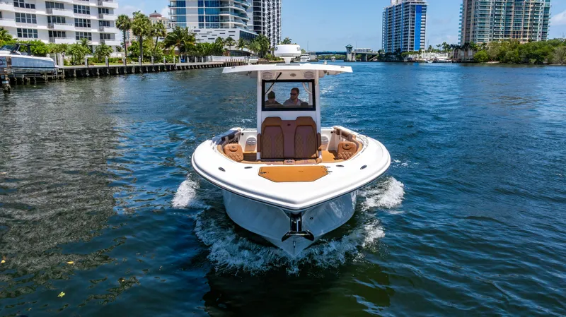 Slide: The Image of 2023 Sea Pro 320 DLX Offshore boat cruising in a scenic urban waterway. - 5