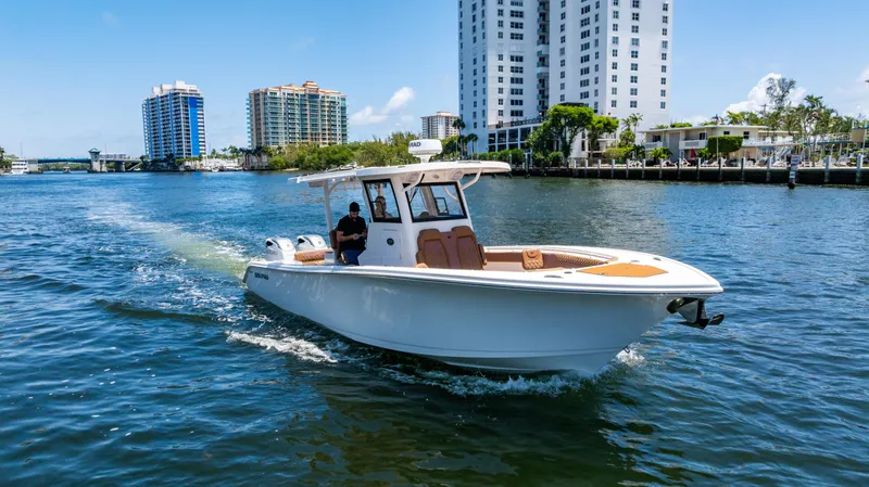 Slide: The Image of 2023 Sea Pro 320 DLX Offshore boat cruising on a sunny day near waterfront buildings. - 6