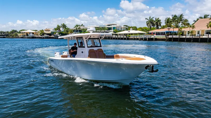Slide: The Image of 2023 Sea Pro 320 DLX Offshore boat cruising on a sunny day near waterfront homes. - 7