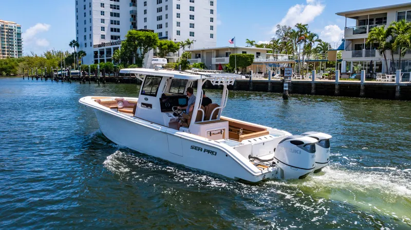 Slide: The Image of 2023 Sea Pro 320 DLX Offshore boat cruising on a sunny waterfront near modern buildings. - 8