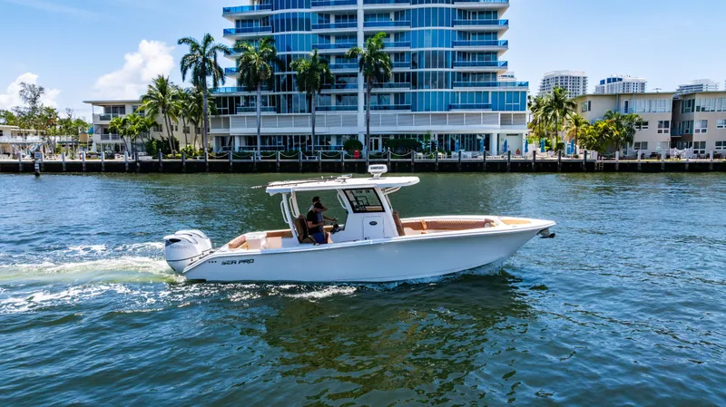 Slide: The Image of 2023 Sea Pro 320 DLX Offshore boat cruising near waterfront buildings. - 9