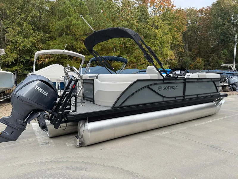 Slide: The Image of 2025 Godfrey Sweetwater 2086 SB pontoon boat with Yamaha motor, parked outdoors. - 2