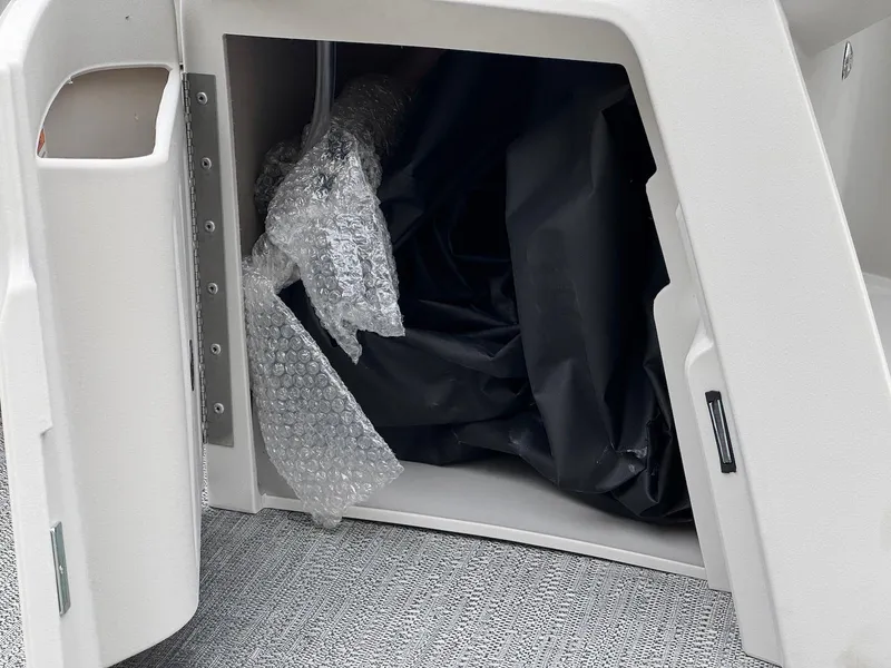 Slide: The Image of Storage compartment of 2025 Godfrey Sweetwater 2086 SB boat with bubble wrap and black cover. - 28