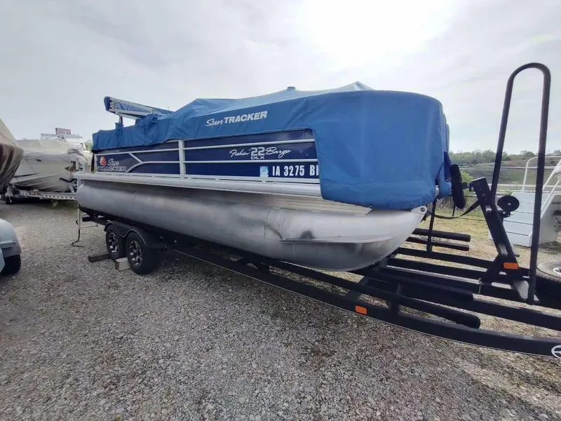 Slide: The Image of 2016 Sun Tracker Fishin' Barge 22 DLX pontoon boat on trailer, covered with blue tarp. - 14